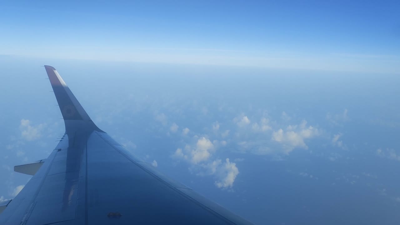 Sky Glider: A Journey Beyond the Clouds – Video Shot showcasing serene skies, graceful wing motion, and soft cloud layers as the airplane glides through tranquil blue altitudes above the Earth