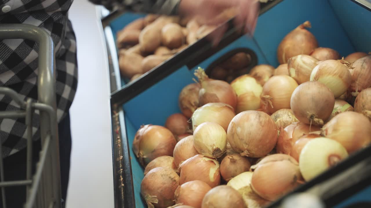Grabbing of onions by shopper during daytime in store.