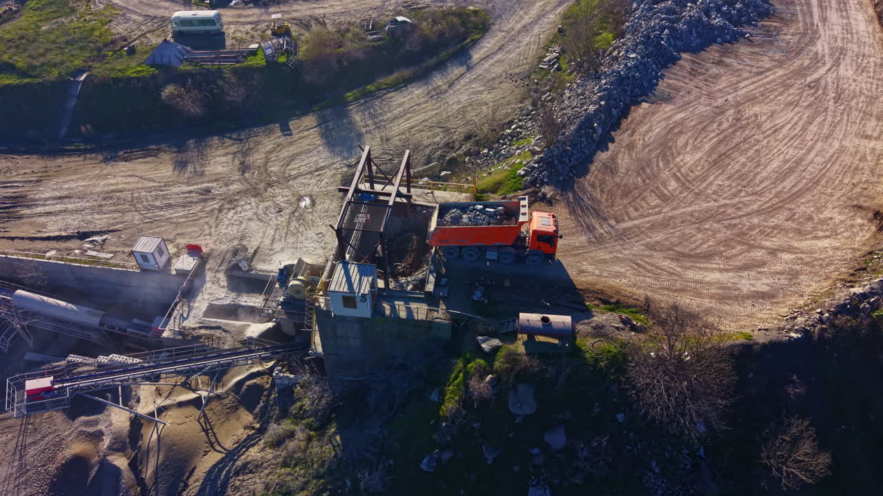 Heavy machinery works on construction site near gravel pit under clear blue sky