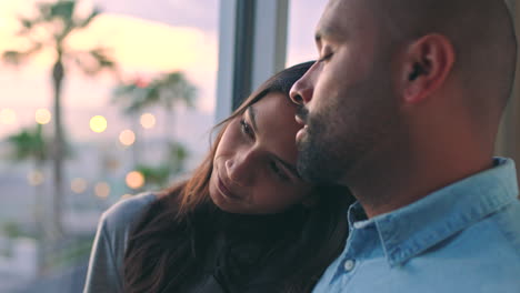 una pareja apoyándose en la ventana al atardecer.