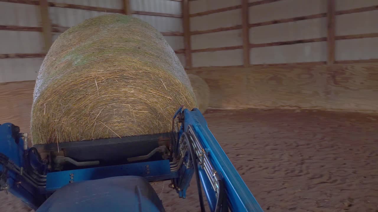 tractor que lleva una bala de heno dentro de un granero, pov conduciendo tractor compacto