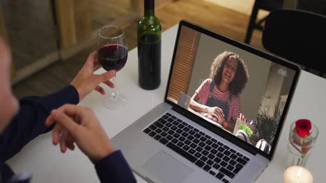 Sección-Media-De-Una-Mujer-Afroamericana-Sosteniendo-Una-Copa-De-Vino-Mientras-Realiza-Una-Videollamada-En-Una-Computadora-Portátil-En-Casa