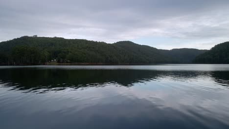 Lake-Barrington-above-water-motion-shot-with-cloud-reflections-near-Sheffield-in-Tasmania,-Australia