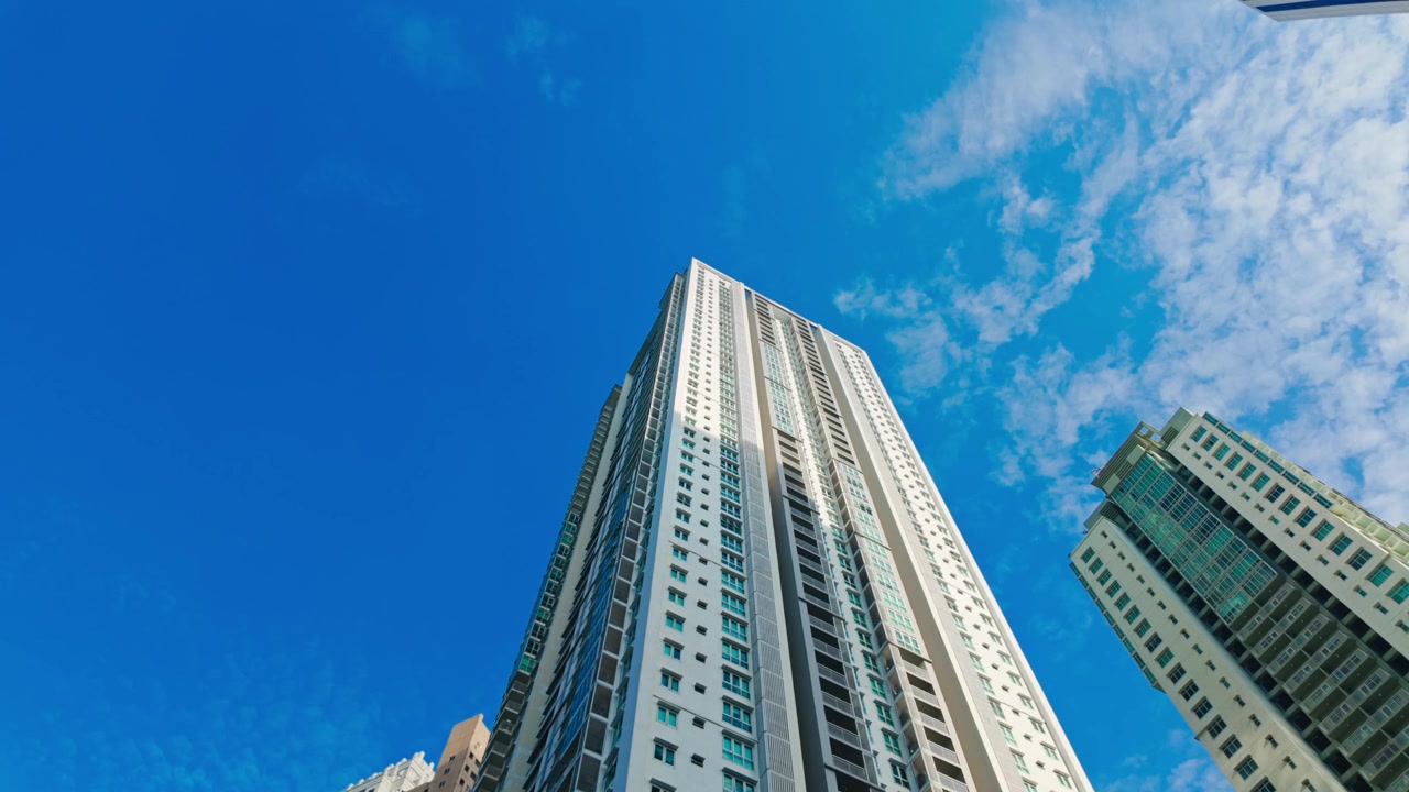 Facciata di un edificio dello skyline cittadino contemporaneo che svetta verso l'alto sotto una luce intensa.