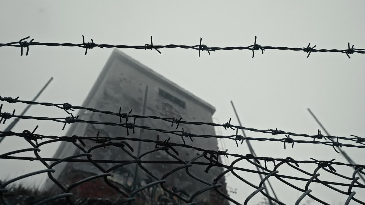 Ominous Barbed Wire Fence with Building in Thick Fog