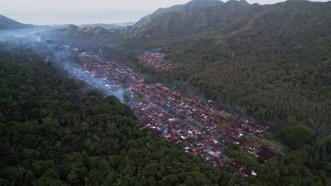 Aerial drone video of a historic Indonesian town in a quiet valley featuring rural charm, traditional wooden houses, and thatched roof architecture reflecting cultural heritage and timeless beauty