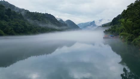 An-early-morning-drone-shot-on-a-low-lever-along-the-beautiful-river-surrounded-by-majestic-mountains