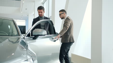 car salesman showing a car to a customer in a showroom
