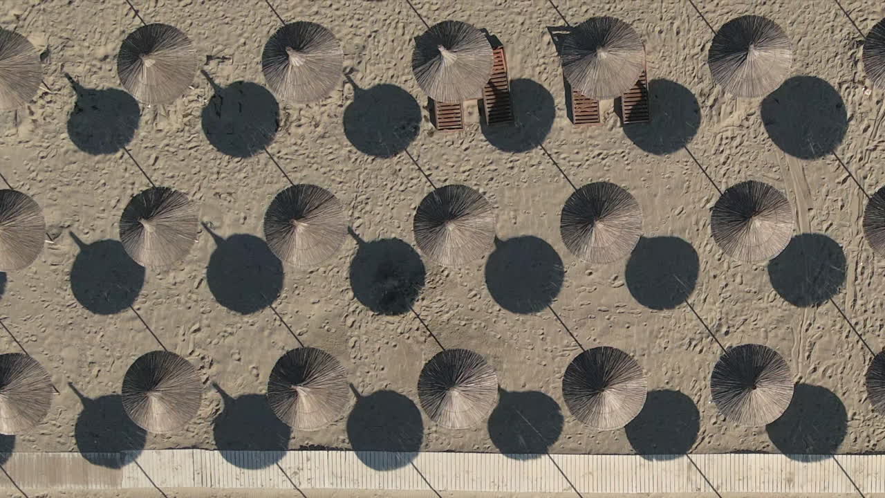 짠 잔디 비치 파라솔은 햇볕이 잘 드는 해변에서 기하학적 패턴을 형성합니다.