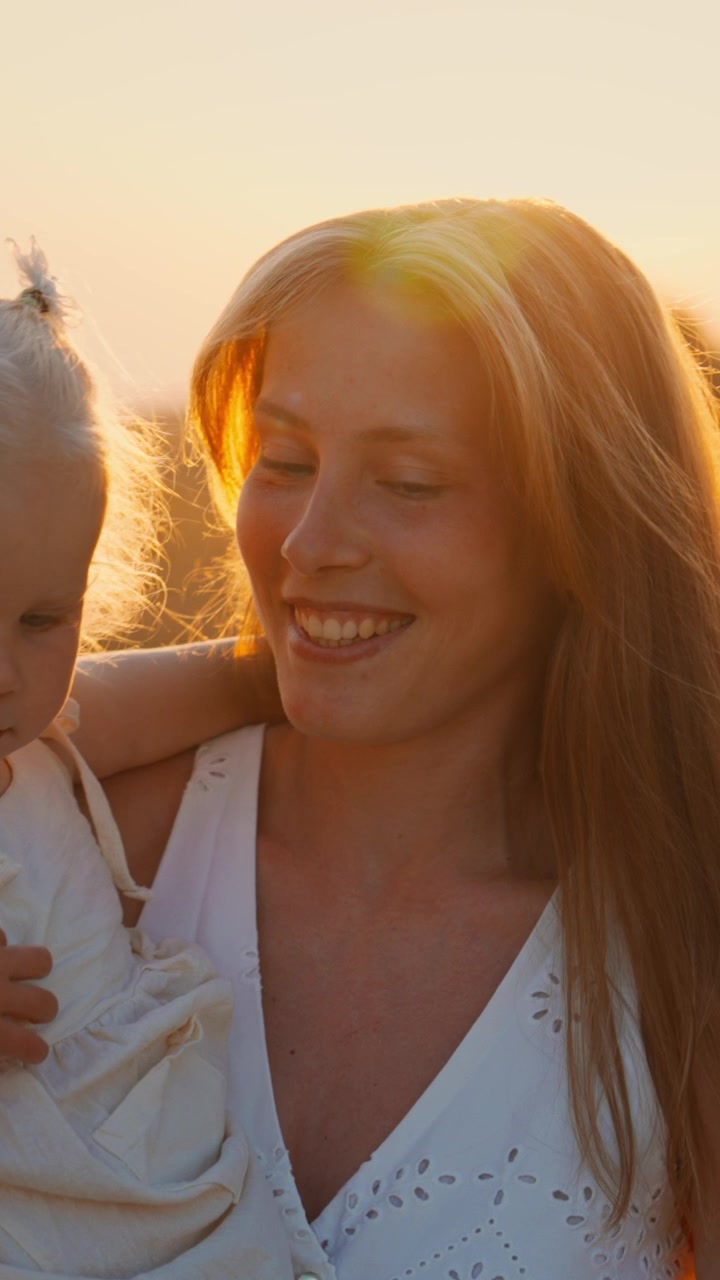 Mutter hält ihre kleine Tochter auf einem Feld zur goldenen Stunde