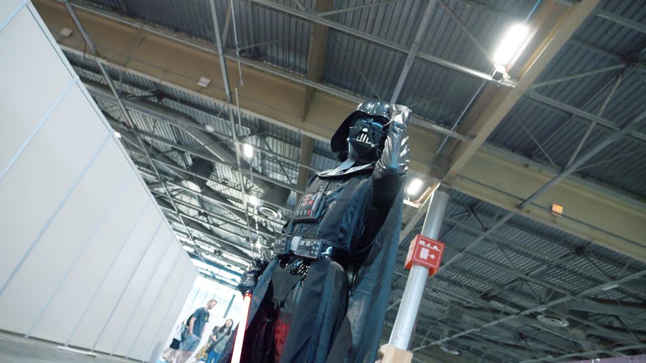 toma cinematográfica de darth vader levantando y levantando el puño en una convención de cosplay