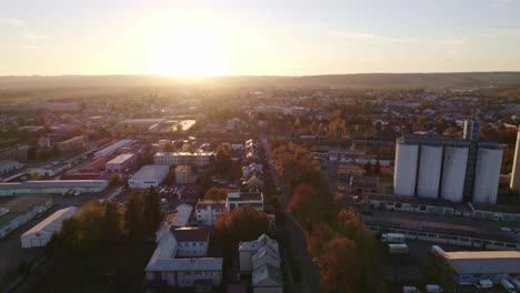 Vuelo-De-Drones-Sobre-La-Calle-De-Otoño-Con-árboles-Y-Complejo-De-Fábrica-Con-Silo-Al-Atardecer