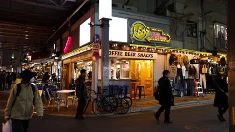 pedestrians walking past shops at night