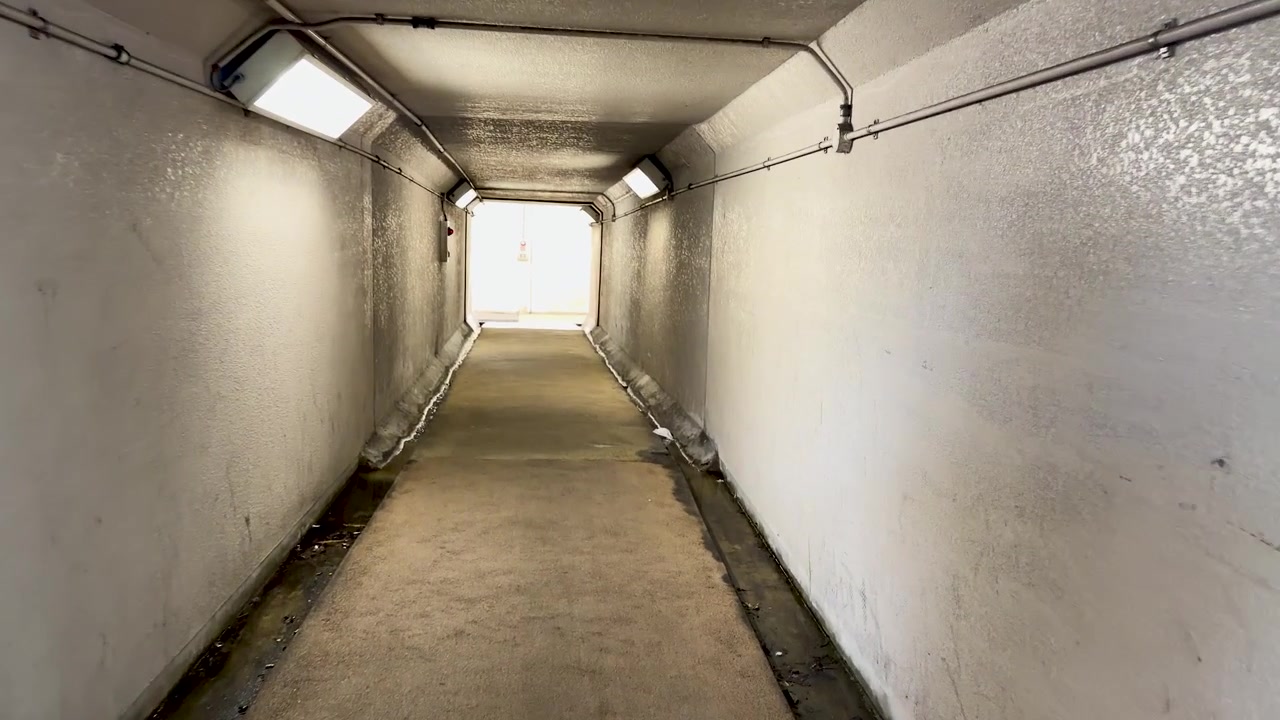 Gehen durch einen hell beleuchteten Beton-Fußgängertunnel.