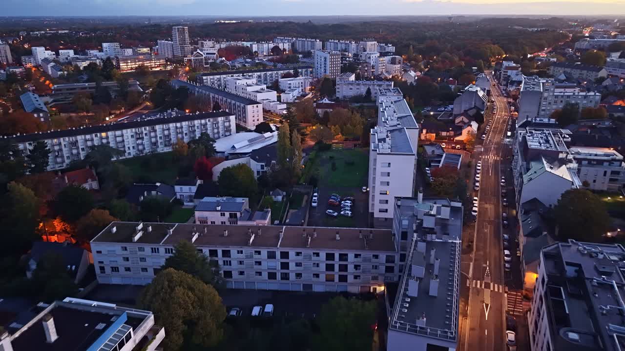 Quartiere Maurepas con strade illuminate ed edifici residenziali al crepuscolo nella città di Rennes, Francia. Drone aereo in avanti.