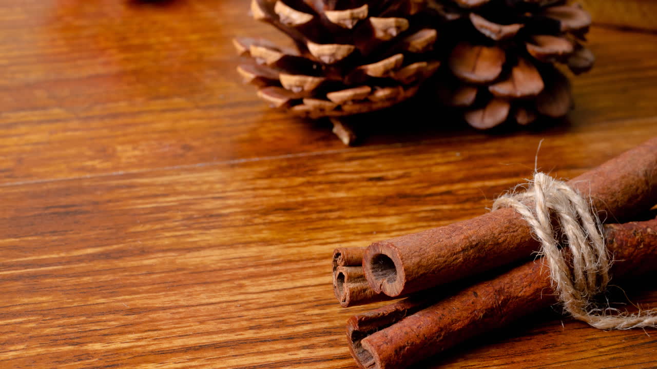 Composition of christmas decorations with cinnamon, pine cones on wooden surface