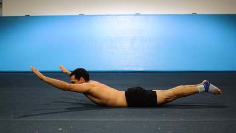 un tipo haciendo una sujeción estática en un gimnasio de gimnasia ejercitando sus abdominales y músculos centrales todavía disparados