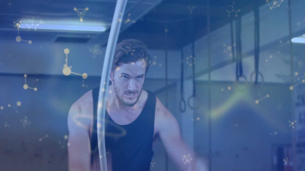 Athlete planting feet and making battle rope waves for conditioning in gym, blue molecular overlays