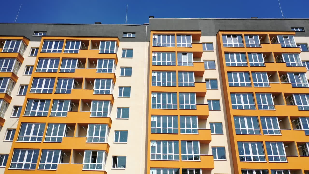 Facade of a new apartment building. Modern multi storey house with bright walls. Block of flats with large balconies. Front view.