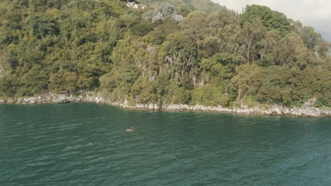 Beautiful-drone-aerial-rotating-shot-of-a-man-paddling-in-the-beautiful-lake-Atltan,-Guatemala