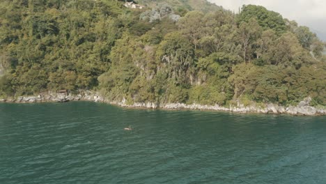 hermosa toma giratoria aérea de drones de un hombre remando en el hermoso lago atltan, guatemala