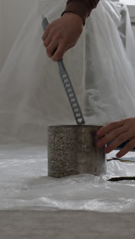 opening an old paint can with a scraper