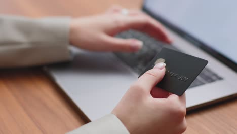 close up female holding plastic credit card, typing on laptop, using online banking service. e-commerce, e-business