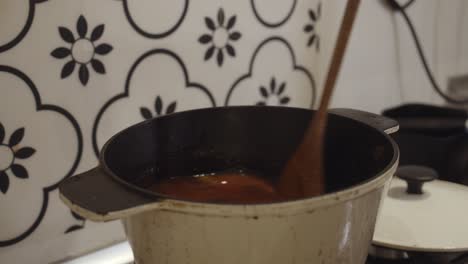 mixing biriyani spiced rice in hot cooking pot with a wooden spoon