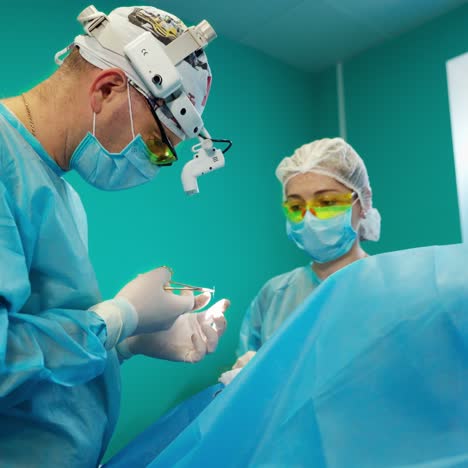 surgery in the modern operating room. surgeon and a female assistant performing operation to a patient using medical tools. medicine concept.
