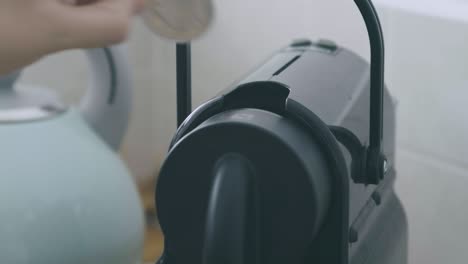 Close-up-of-a-A-hand-inserts-a-coffee-pod-into-a-machine,-positions-the-cup,-and-lets-the-coffee-pour-down-in-slow-motion