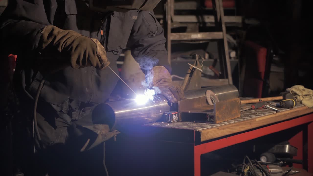 Man shielded metal arc welding stainless steel pipe in workshop