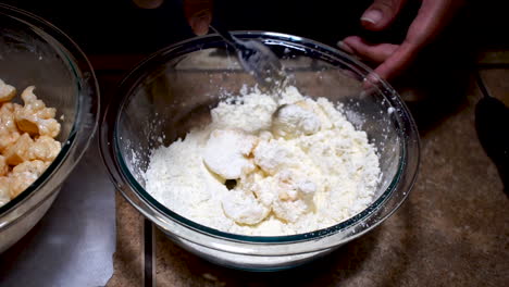 stirring cauliflower in flour mix with fork while breading, slow motion