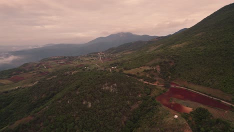 Aerial-view-of-green-hilly-mountains-rising-to-the-clouds