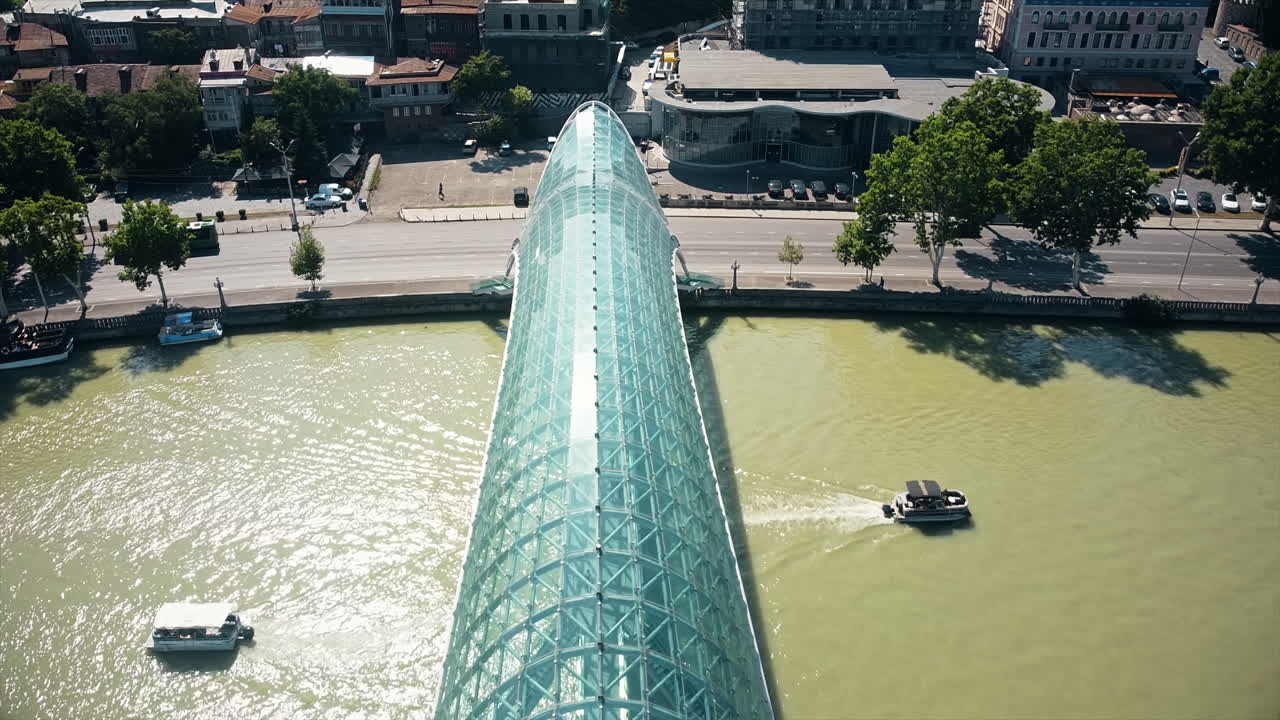 Aerial drone view of Tbilisi, Georgia. Kura river with a modern bridge over it, a lot of greenery, floating boats