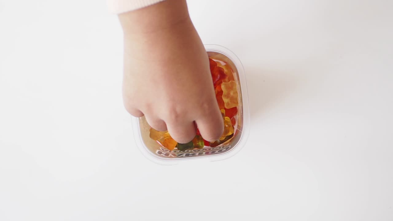 la mano del niño alcanzando a los osos de goma en un recipiente