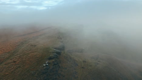 Large-bare-rocky-cliffs,-outcrop-with-small-dense-white-fog-and-grey-clouds