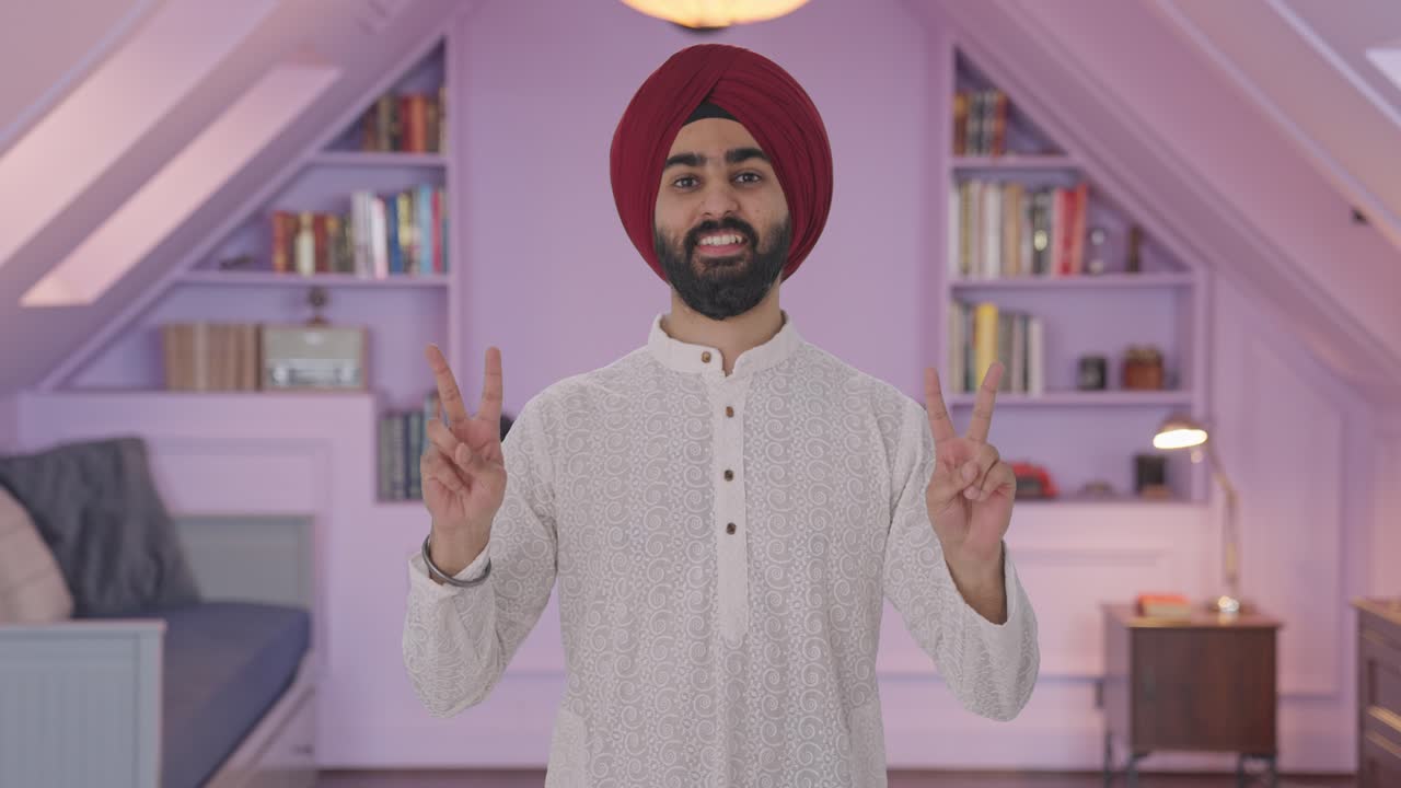 Uomo indiano Sikh felice che mostra il segno della vittoria