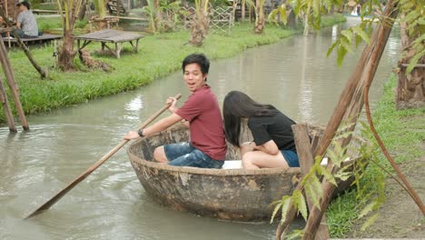 young asian couple are rowing a circle boat in a canal.