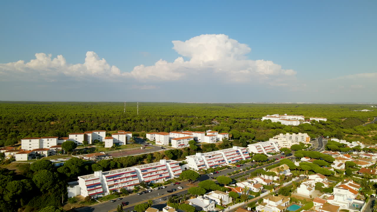 vista aérea de hoteles, villas privadas de alquiler y apartamentos en la costa de la ciudad de el rompido con un hermoso horizonte nublado