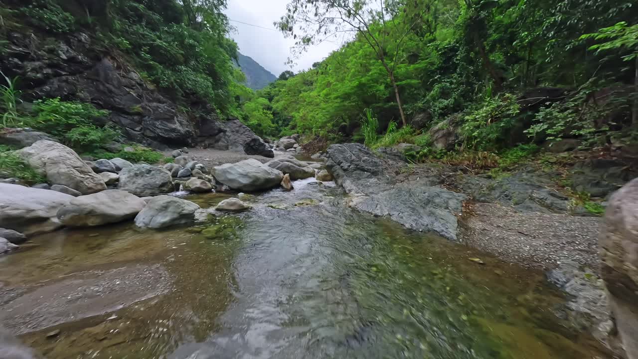 Drone che vola basso sull'acqua del ruscello che scorre tra le rocce in un'area selvaggia, Las Yayitas, Bani nella Repubblica Dominicana