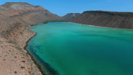 Aerial-view-moving-forward-Ascending-shot,-Scenic-view-emerald-green-sea-of-of-Isla-Espiritu-Santo-in-Baja-Sur-Mexico,-rocky-cove-in-the-background