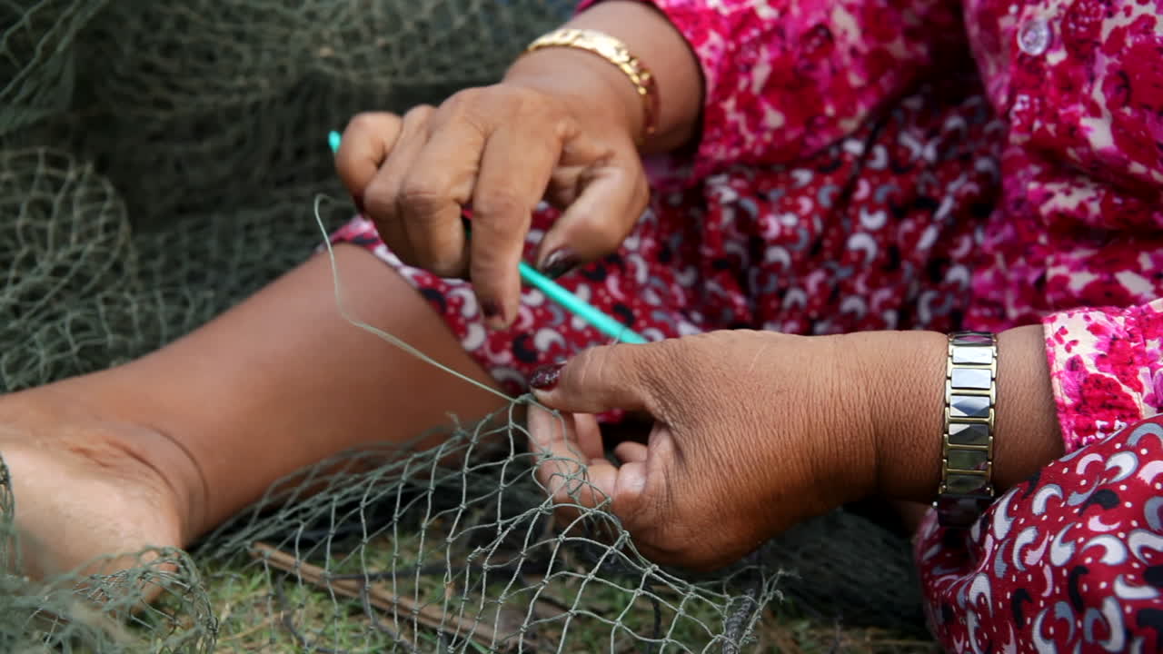 mujer reparando una red de pesca en camboya