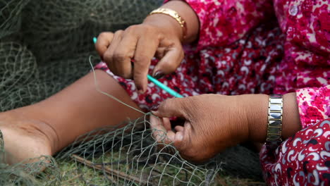 woman repairing a fishing net in cambodia
