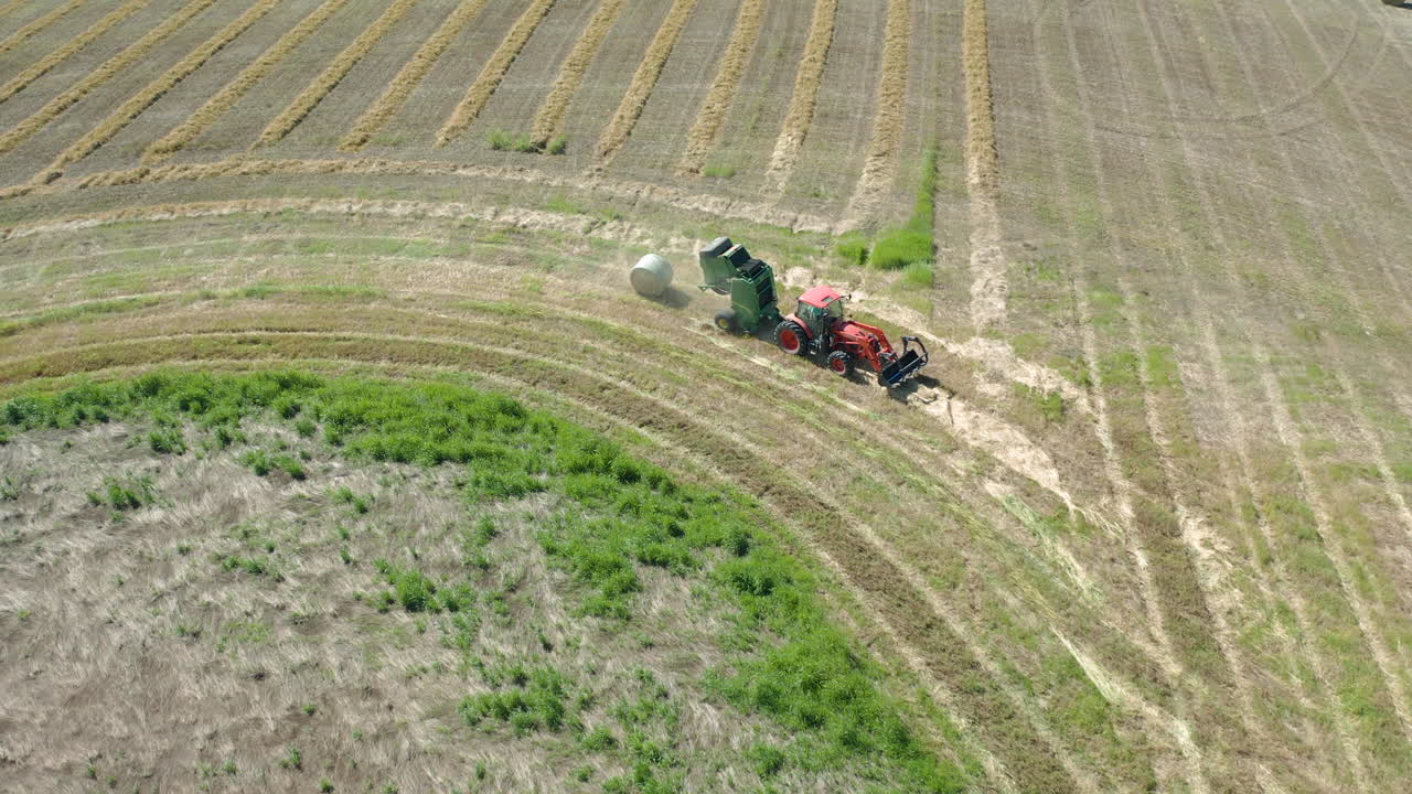 una empacadora de heno empacando heno en la granja en saskatchewan, canadá, cuando hace buen tiempo - tiro de ángulo alto