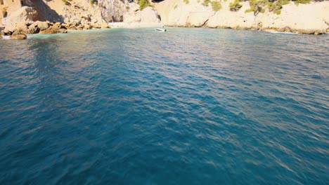 deep blue ocean water shimmers as friends play in waters of beach, aerial dolly tilt up