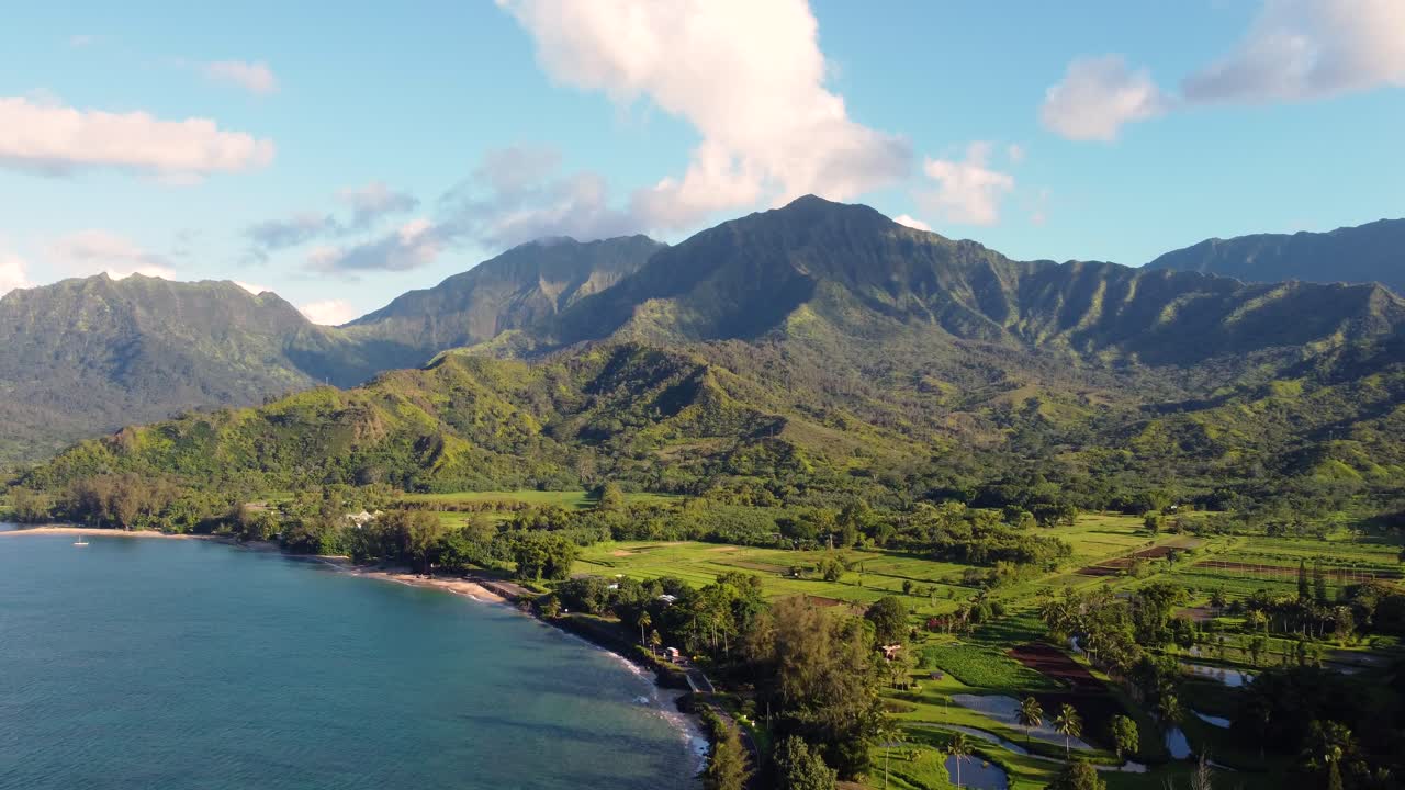 Cinematic Aerial shot of Hanalei Bay and green mountains, beach, boat, ocean with the Hanalei River near Princeville, Kauai, Hawaii