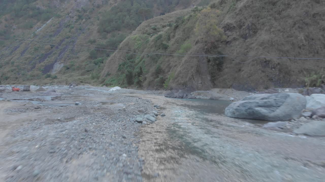 three male hikers walking down Natural mountain water river flowing under metal steel iron bridge valley remote region fast approaching wide aerial under crossing over rapids white water Philippines