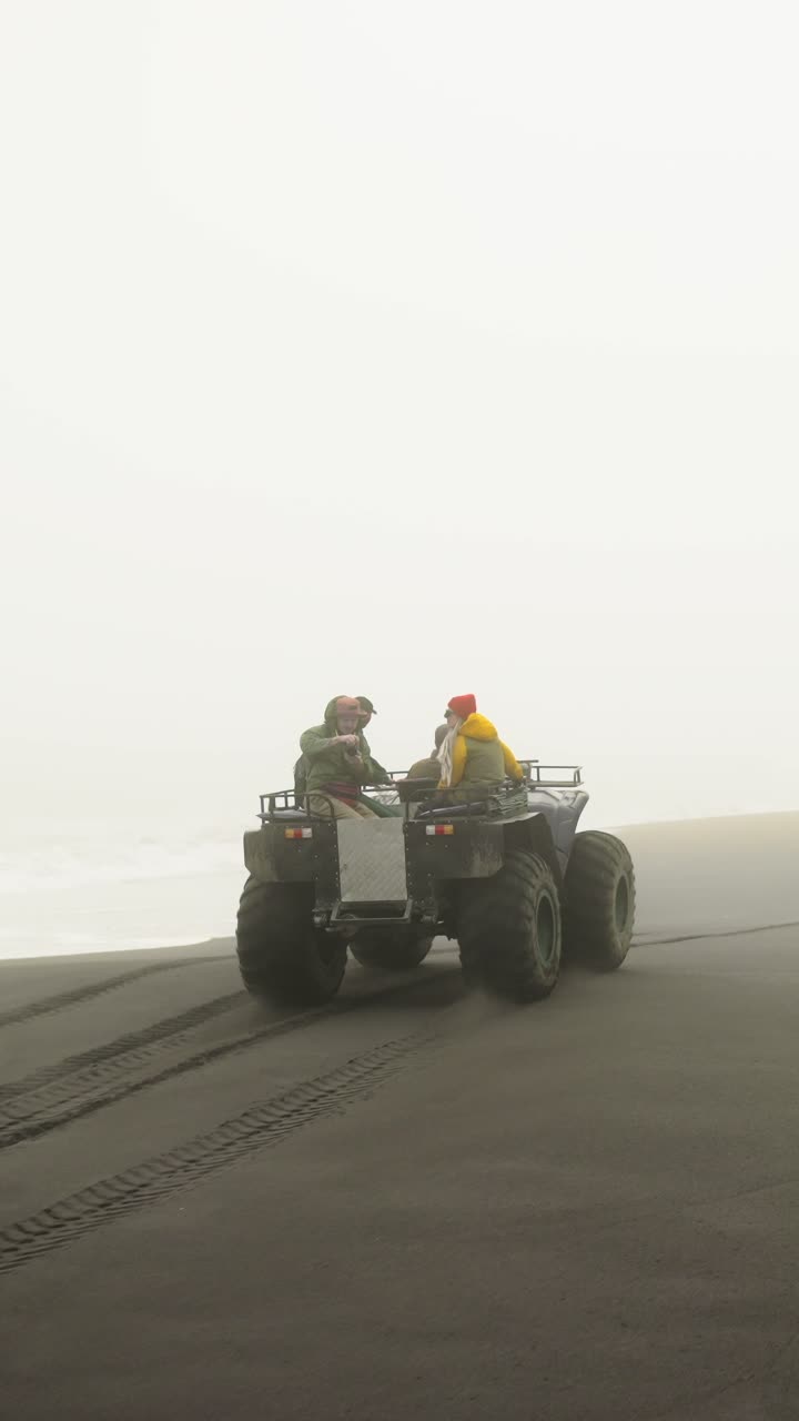 Due Persone in Quad su una Spiaggia di Sabbia Nera Nebbiosa