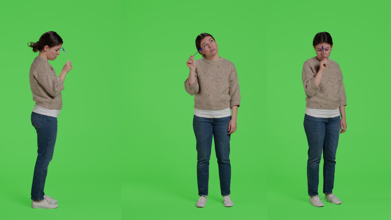Woman in sweater thinking with a pen on green screen
