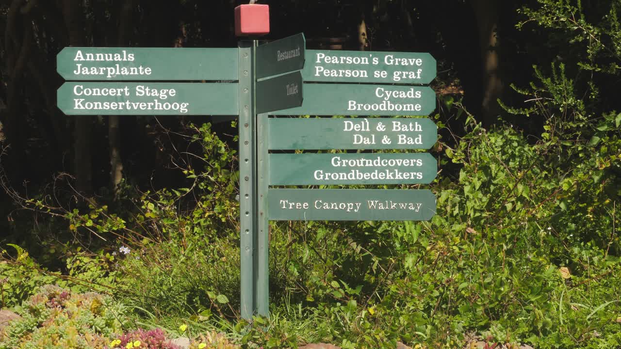 pan a la izquierda del follaje del bosque al cartel en el jardín botánico de ciudad del cabo